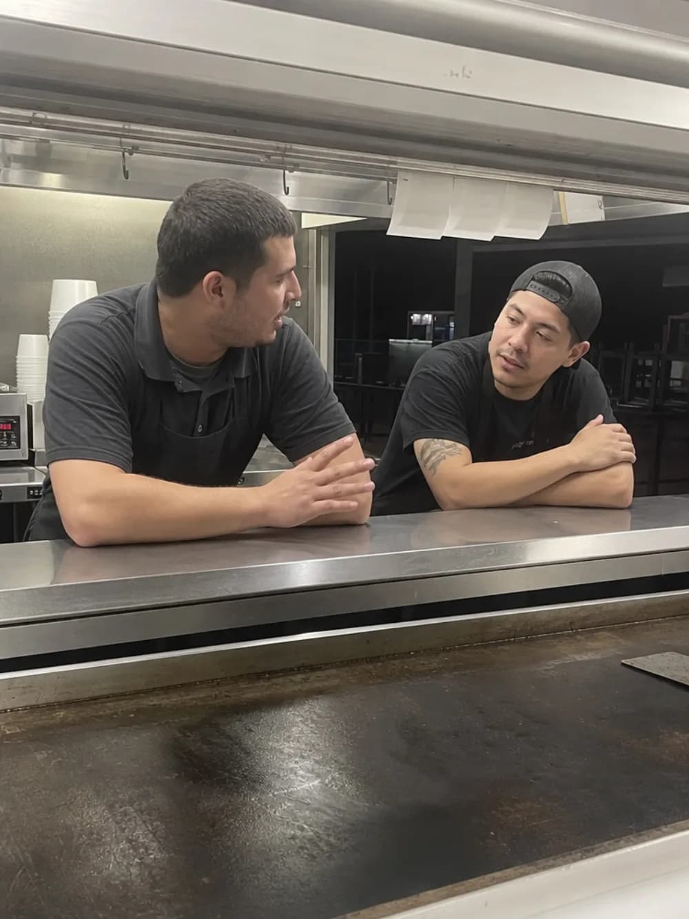 Two cooks talking across the pass after the last ticket of the night