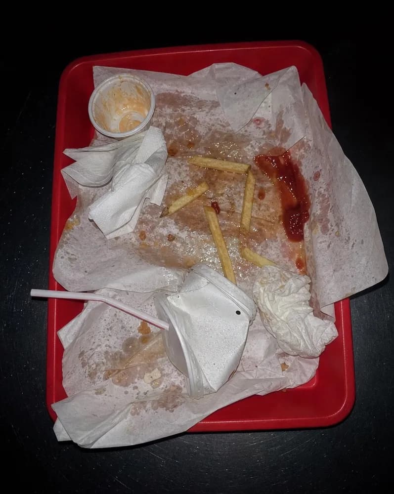 A red tray of crumpled paper and cold fries at the end of a meal