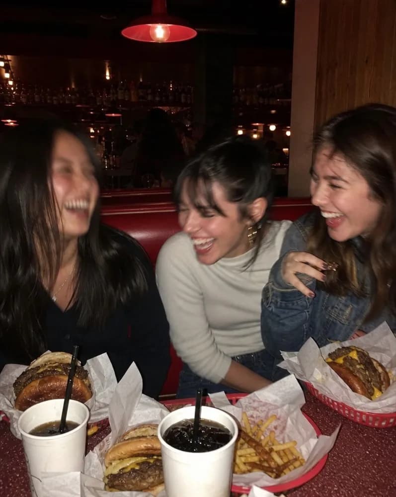 Three friends laughing over burgers in a red booth