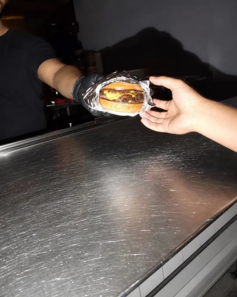 A foil-wrapped burger handed across the counter